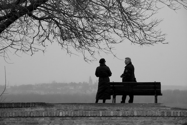 black and white image of two people talking beside a bench. How Do You Tell Your Spouse You Want a Divorce?