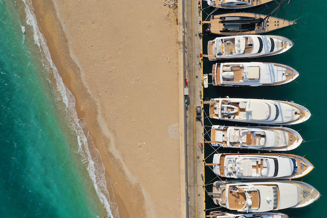 aerial-top-view-photo-of-busy-mediterranean-port-w-2026-03-26-01-59-12-utc aerial view of the tide going out on a mediterranean beach with docked boats. Fluctuation metaphor to highlight the topic of child maintenance variations